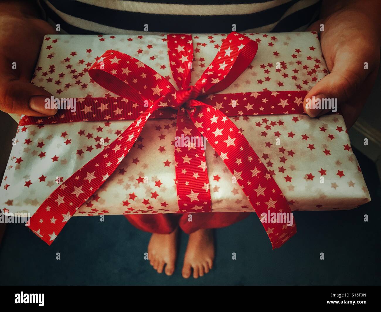 Schön verpackte Weihnachtsgeschenk mit einem roten Band gebunden - Smartphone-aufgenommenes Stockfoto