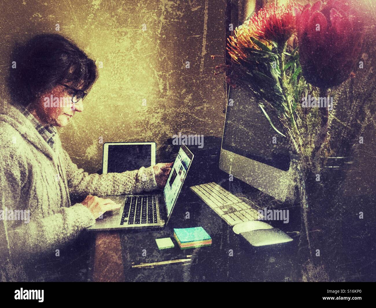 Frau mit Laptop an ihrem Schreibtisch - Smartphone-aufgenommenes Stockfoto