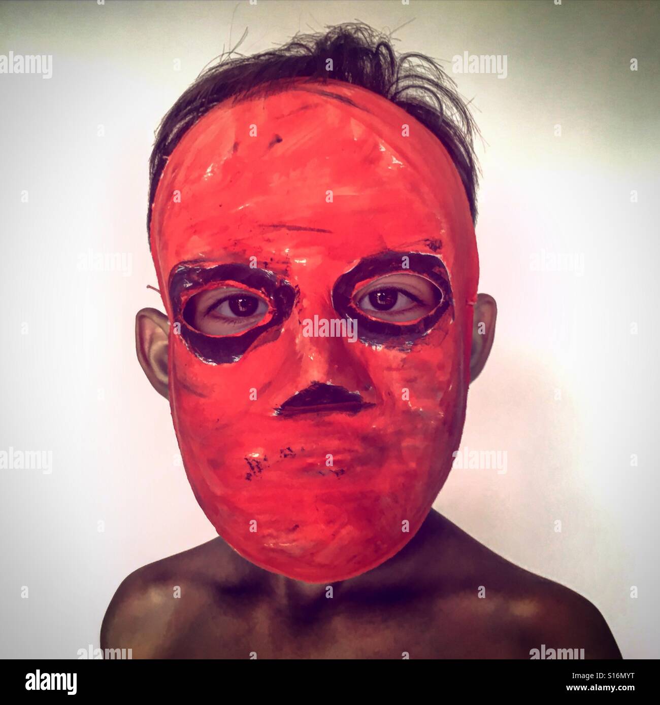 Red Mask Handwerk DIY Gesichtsmaske auf dem Kopf eines Kindes / eines Kindes / von Kindern aufgenommen - Smartphone-aufgenommenes Stockfoto