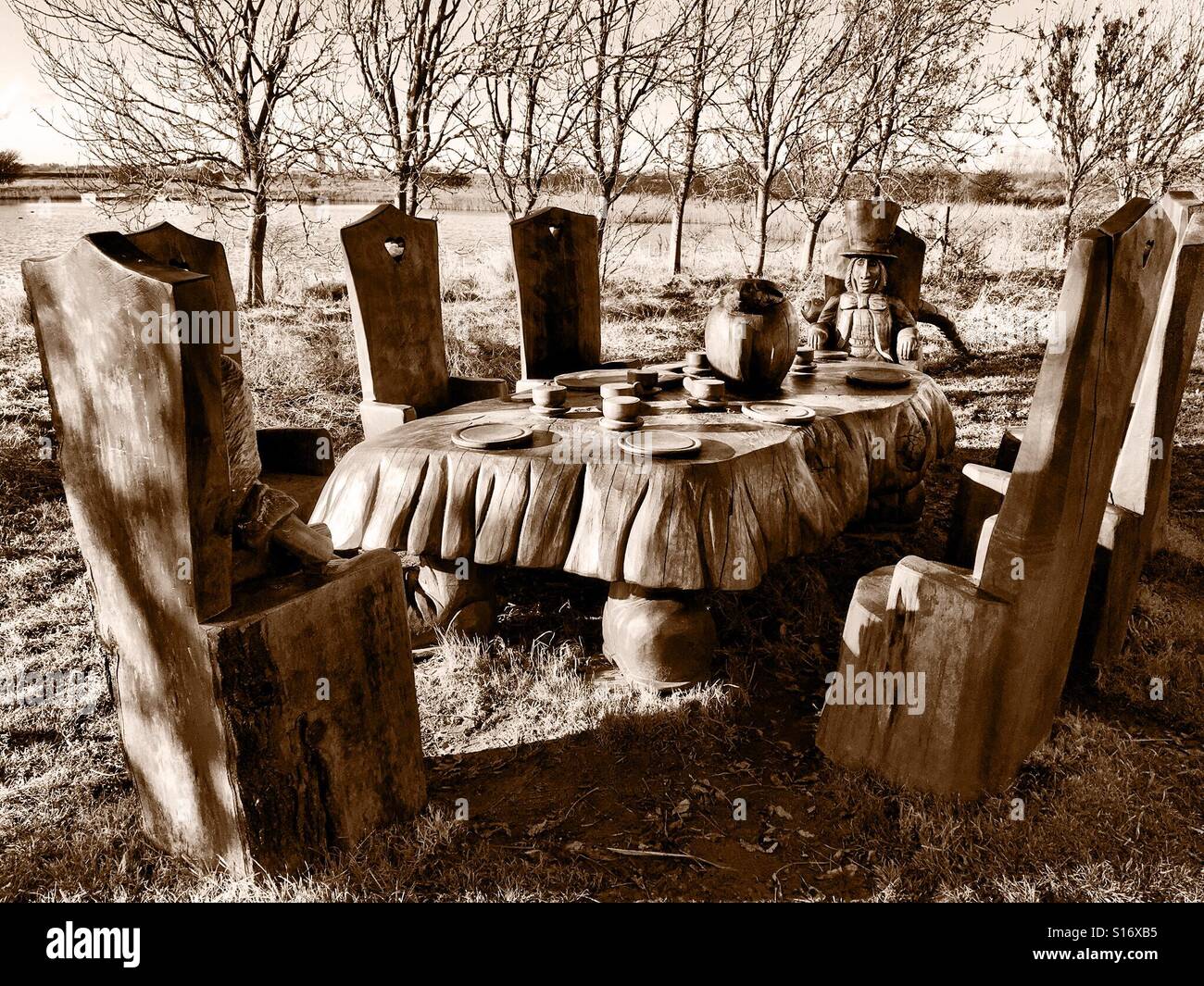 Geschnitzte hölzerne Skulptur der Mad Hatter Tea Party in Sepia-Tönen - Smartphone-aufgenommenes Stockfoto