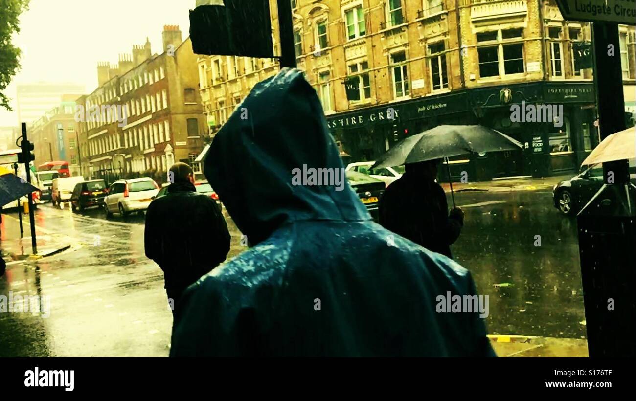 Menschen mit Regenschirmen und Regenjacken umarmen einen schweren Sommer Regen an einer belebten Kreuzung in Clerkenwell, London. Stockfoto