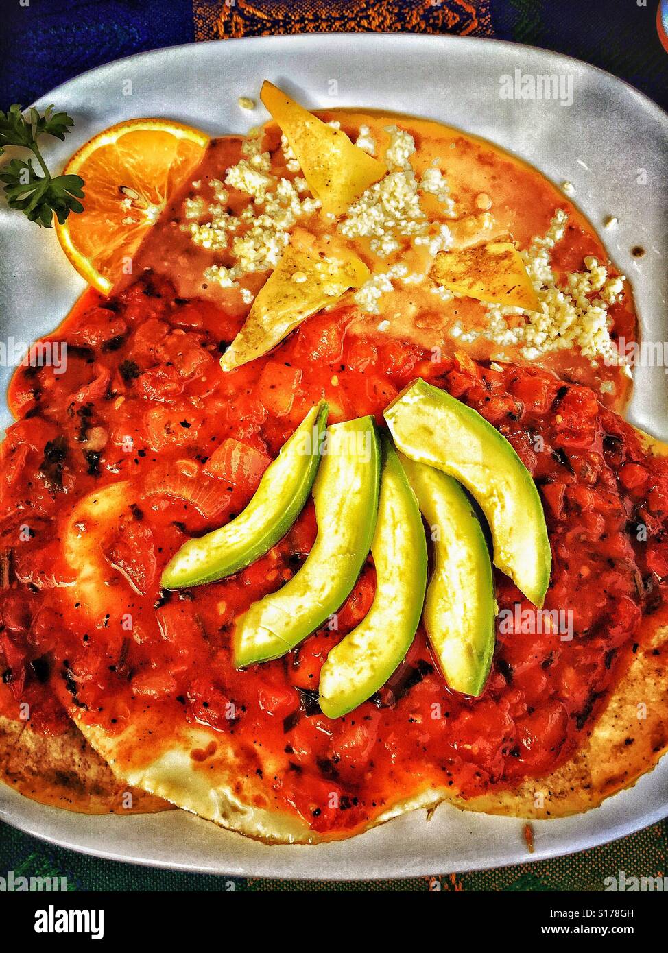 Ein typisches Frühstück in Nayarit einschließlich Huevos Rancheros, garniert mit Avocado und einer Seitenlänge von gebackenen Bohnen. Stockfoto