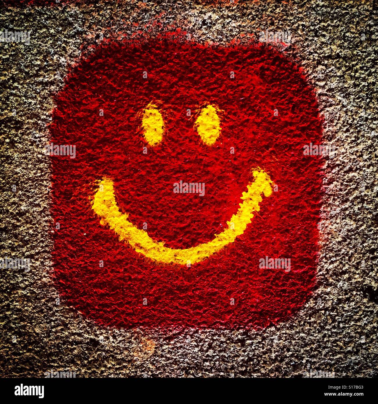 Originales Smiley Smile-Symbol in roter Farbe auf strukturierter Wandstruktur - Smartphone-aufgenommenes Stockfoto