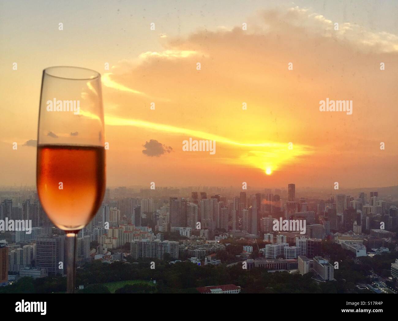 Fangen Sie die goldenen Stunden Singapur Sonnenuntergang mit einem Glas Champagner Stockfoto