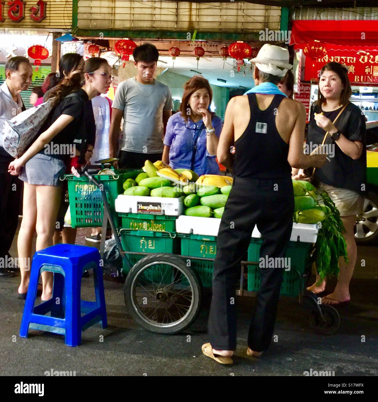 Chinesische Touristen Feilschen mit einem Mango-Verkäufer auf Yaowarat Road in Bangkok Chinatowm, Thailand Stockfoto