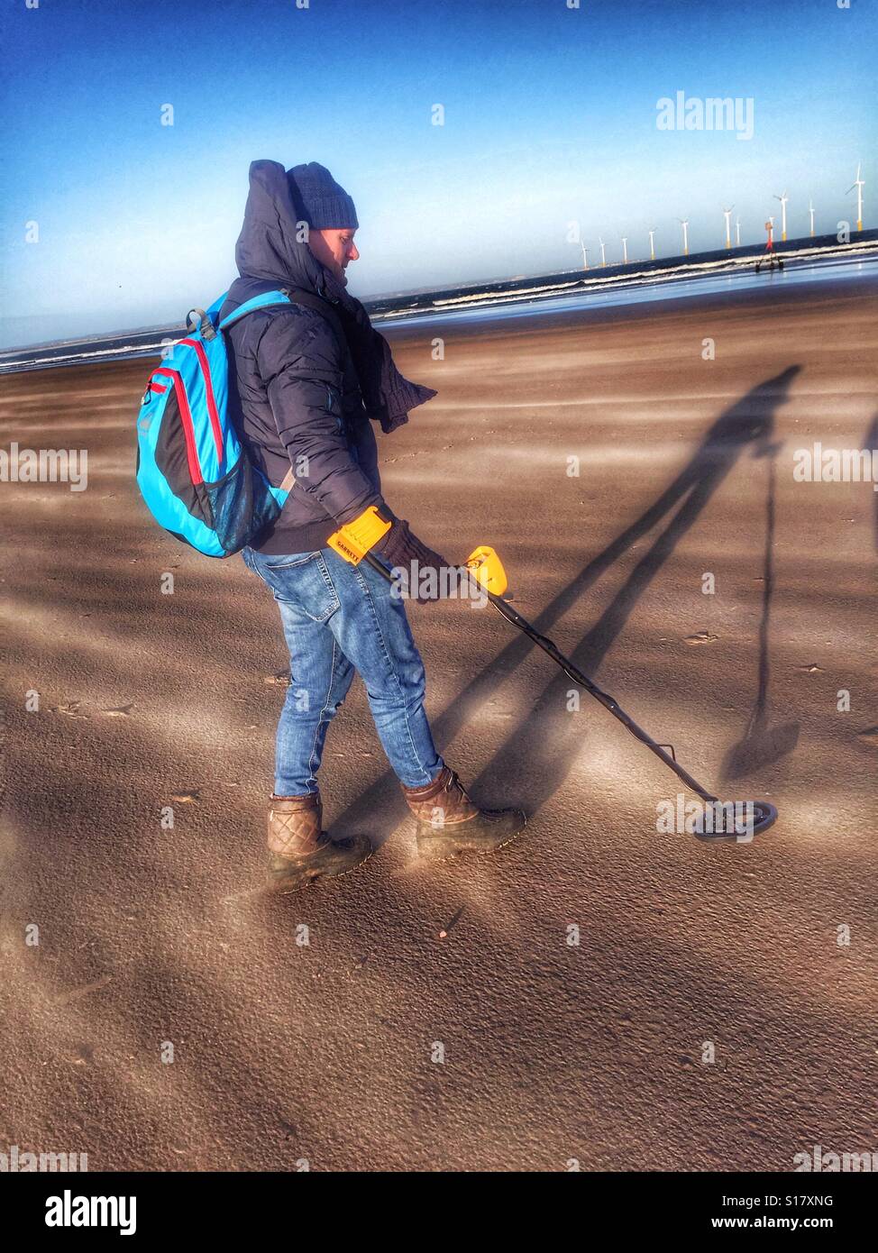 Mann mit einem Metalldetektor auf einem sehr windigen Strand Stockfoto
