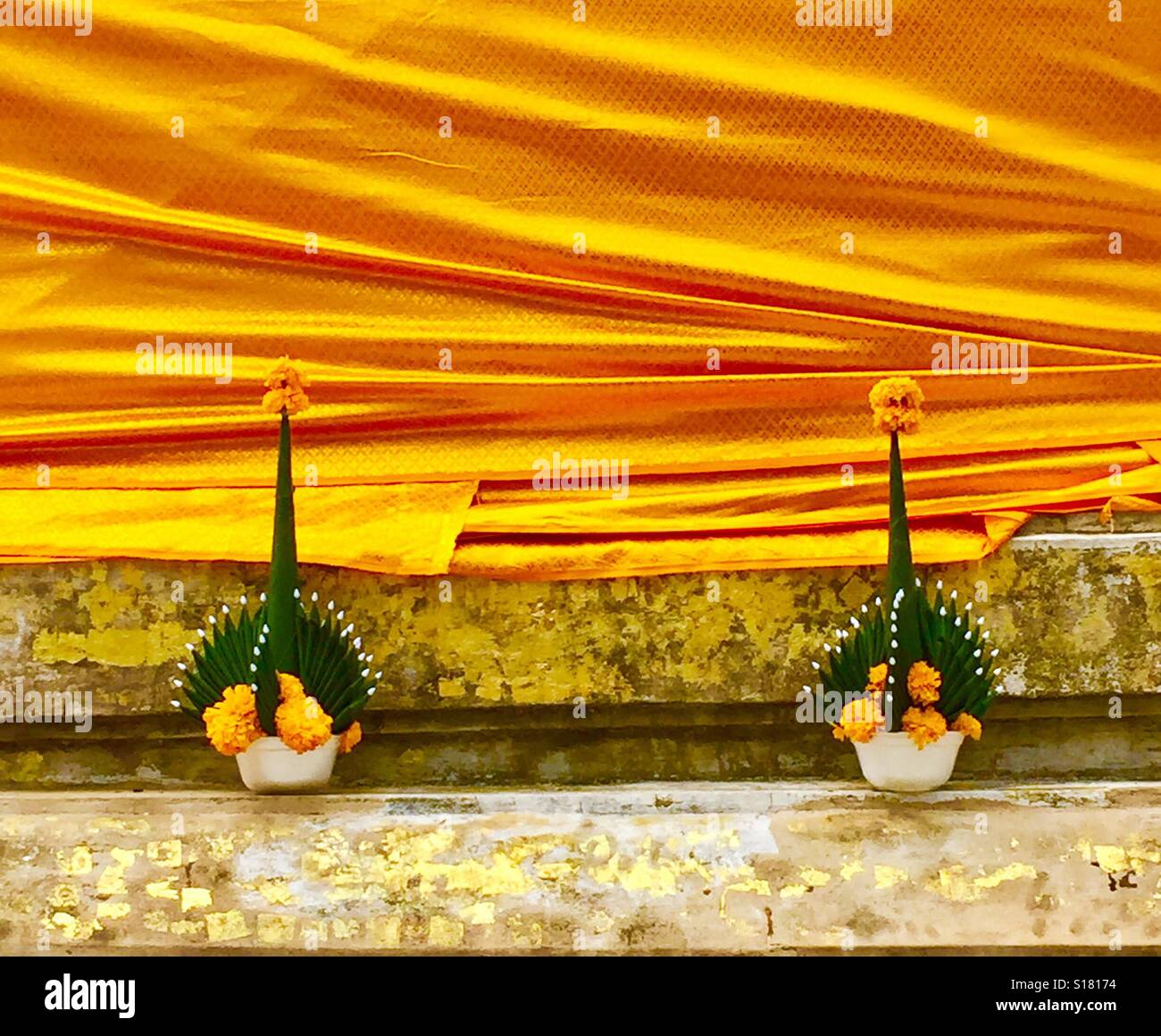 Gelbe seidiges Tuch umwickelt einen Stupa mit zwei Blumensträuße von Thai Ringelblumen Stockfoto