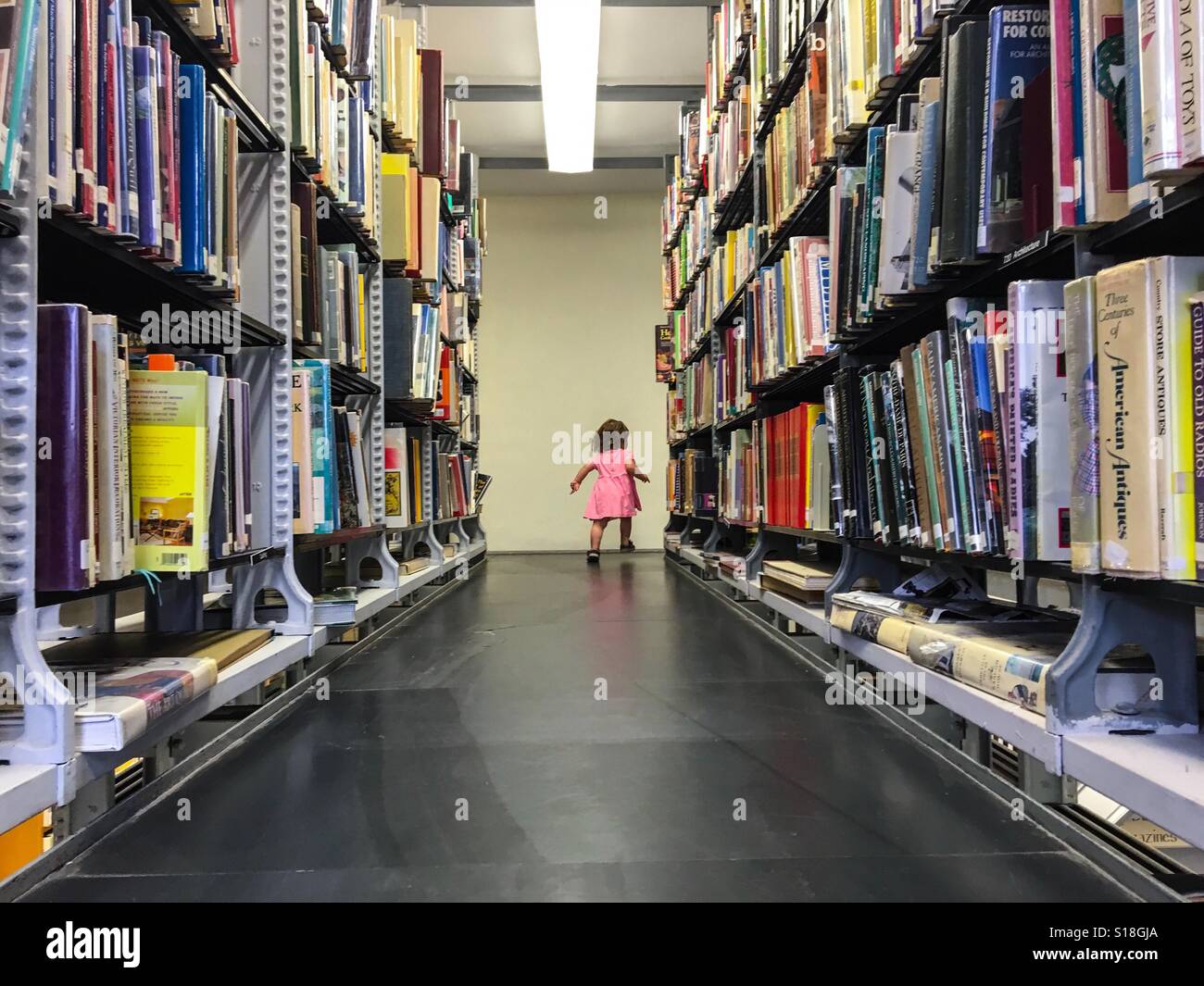 Ein Kleinkind erforscht eine Bibliothek. Stockfoto