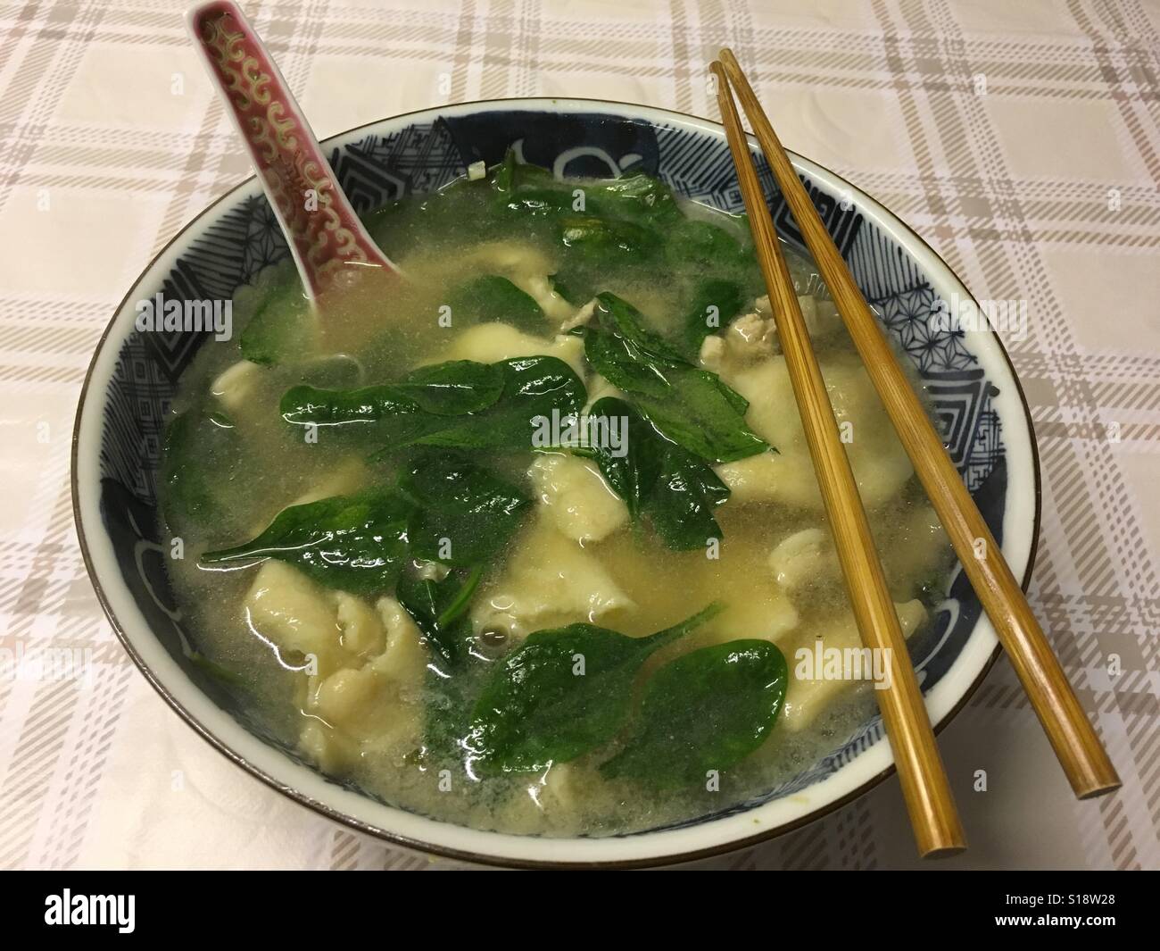 Nudelsuppe mit grüner Spinat, chinesischen Löffel und Stäbchen, Norfolk, Großbritannien - Smartphone-aufgenommenes Stockfoto