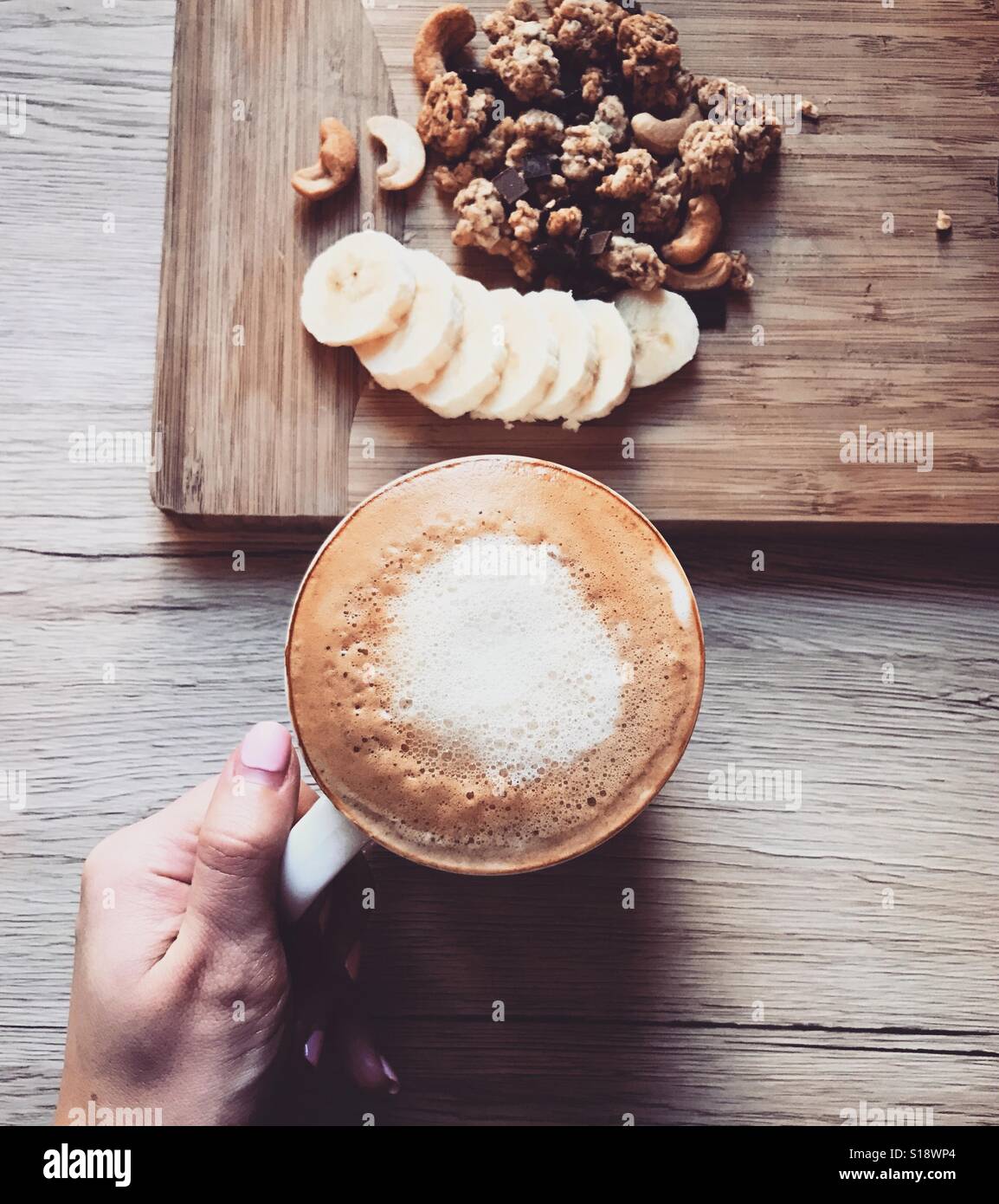 Kaffee am Morgen. Banane und Getreide auf einer Holzplatte und eine Tasse heißen Kaffee. Frühstückstisch Stockfoto