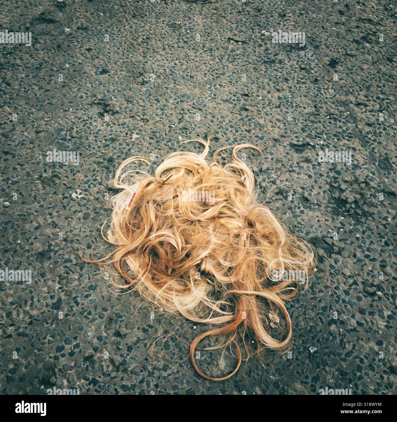 Ein blondes Haarteil oder eine Perücke verworfen, in einer Straße Stockfoto