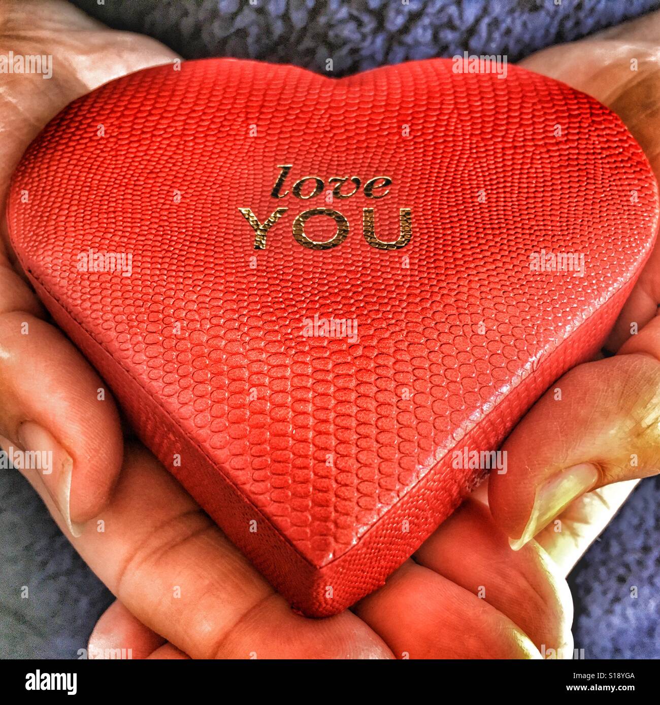 Ich liebe dich, herzförmiges rotes Kästchen in den Händen - Smartphone-aufgenommenes Stockfoto