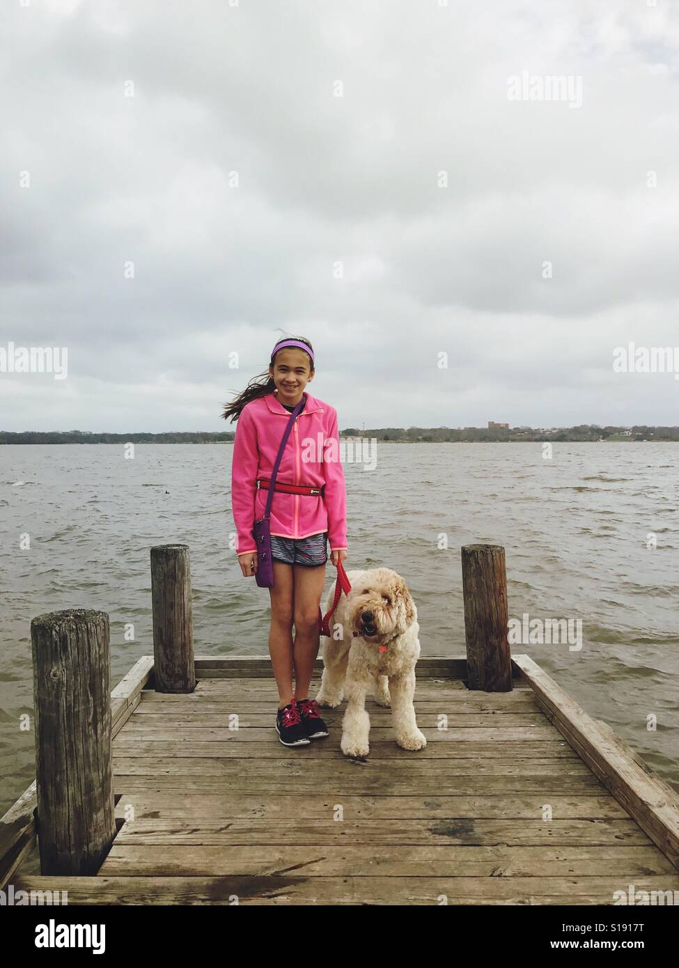 Mädchen und ihr Hund sind am See an einem windigen Tag. Stockfoto