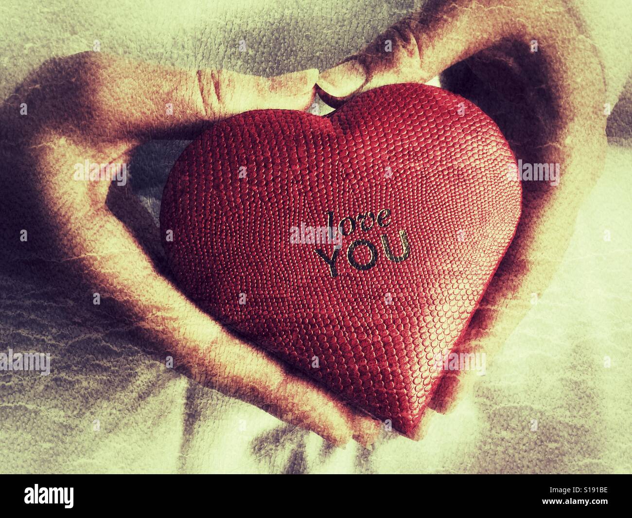 Rote herzförmige Schachtel in Herzform Händen gehalten - Smartphone-aufgenommenes Stockfoto