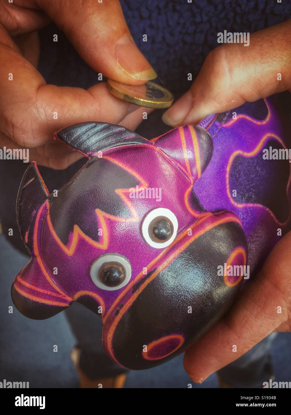 Die Münzen aus einer lila Kuh Lederbeutel. - Smartphone-aufgenommenes Stockfoto