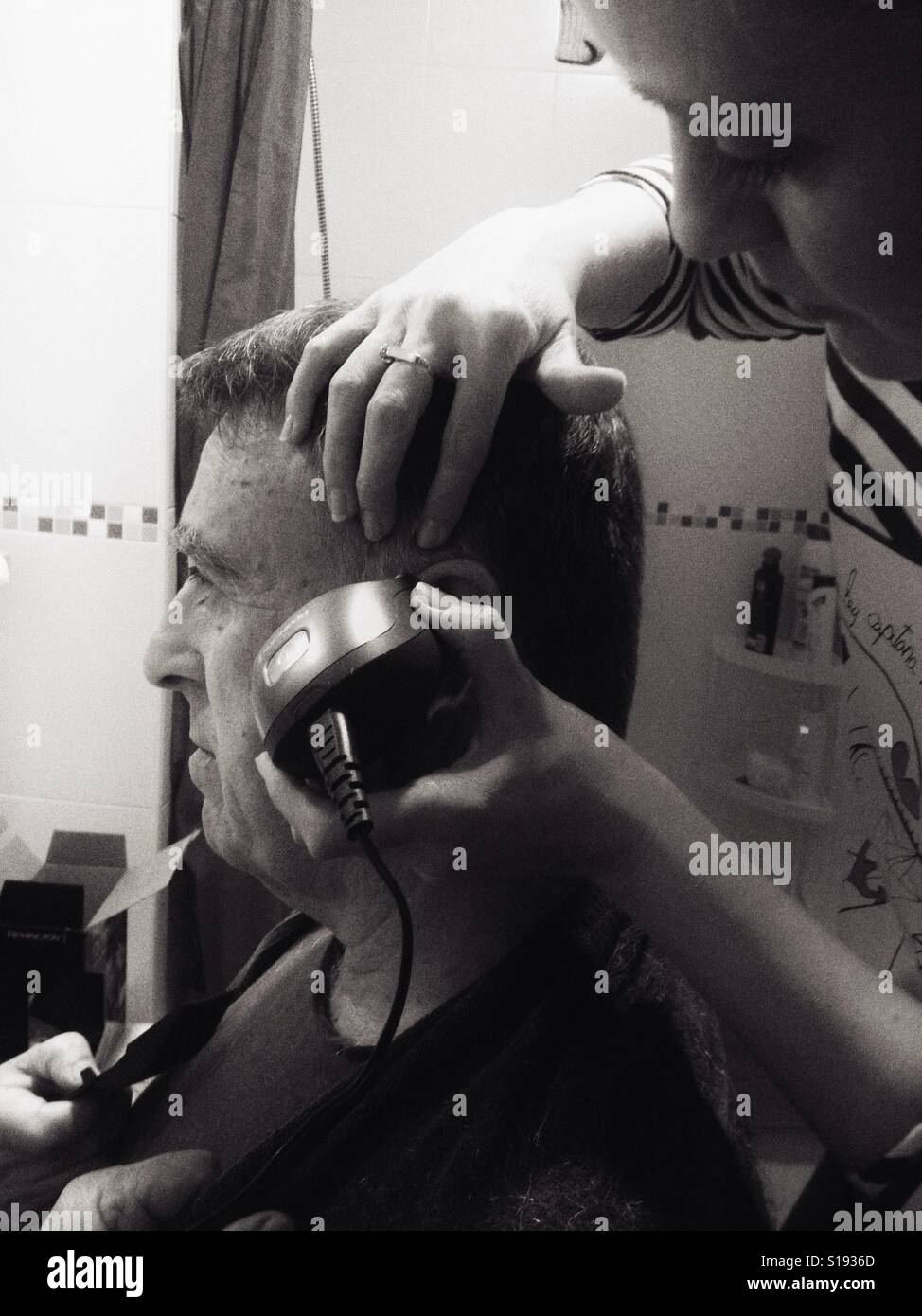 Frau schneiden Mann Haare - Smartphone-aufgenommenes Stockfoto