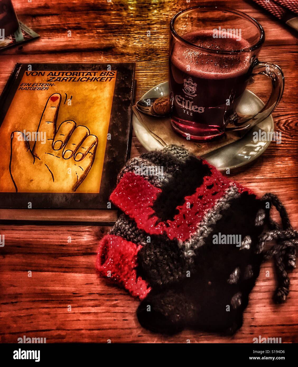 Gemütliche Atmosphäre mit Buch, Glühwein und Winterhandschuhe Stockfoto