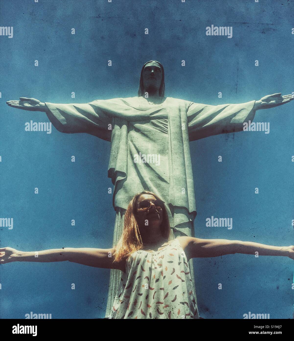Junges Mädchen posiert mit den Armen weit offen vor der Statue von Christus den Erlöser in Rio De Janeiro Stockfoto