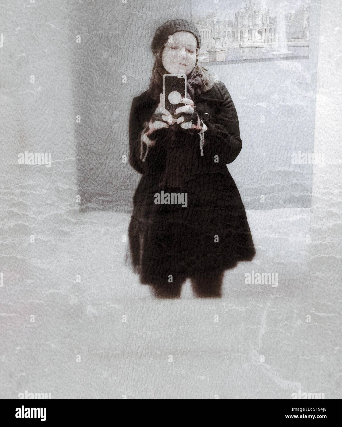 Blick auf ihr Handy, Mädchen gekleidet mit Winterkleidung Stockfoto