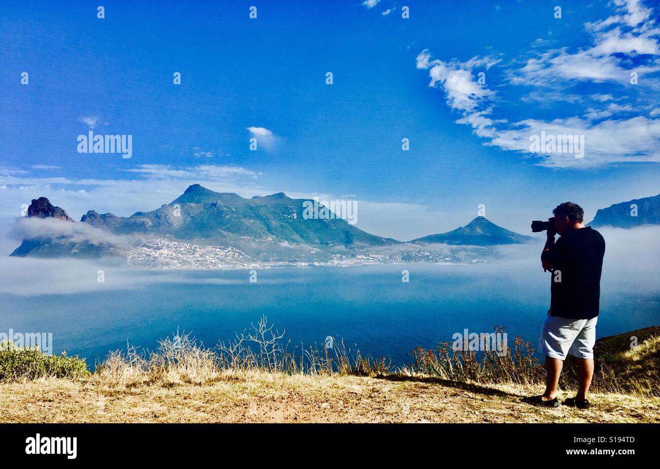 Ein Fotograf, schießen die dramatische und malerischen Landschaften der Hout Bay vom Gipfel Chapman in Cape Town, Südafrika. - Smartphone-aufgenommenes Stockfoto