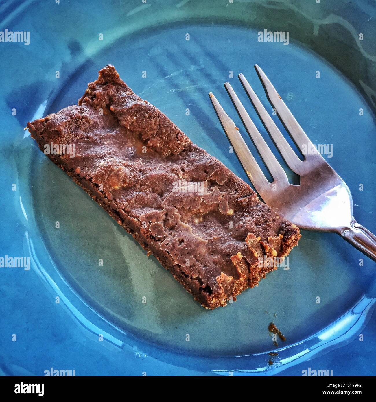 Hausgemachte Rohkakao Brownie Bar auf einen blauen Teller mit einer Gabel einstechen. Stockfoto