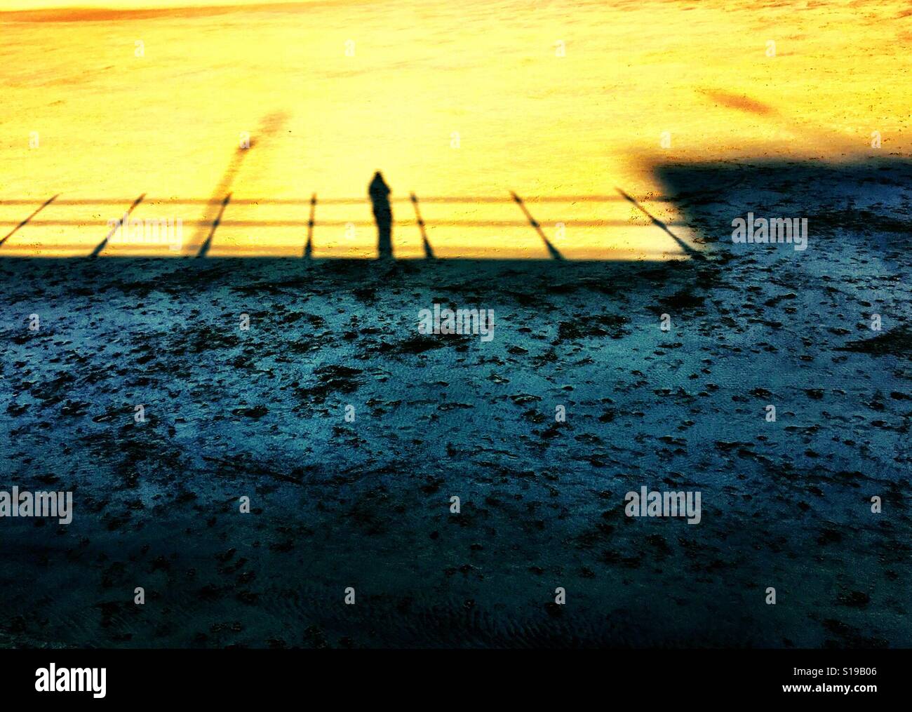 Schatten der Person und Geländer an einem Strand im winter Stockfoto
