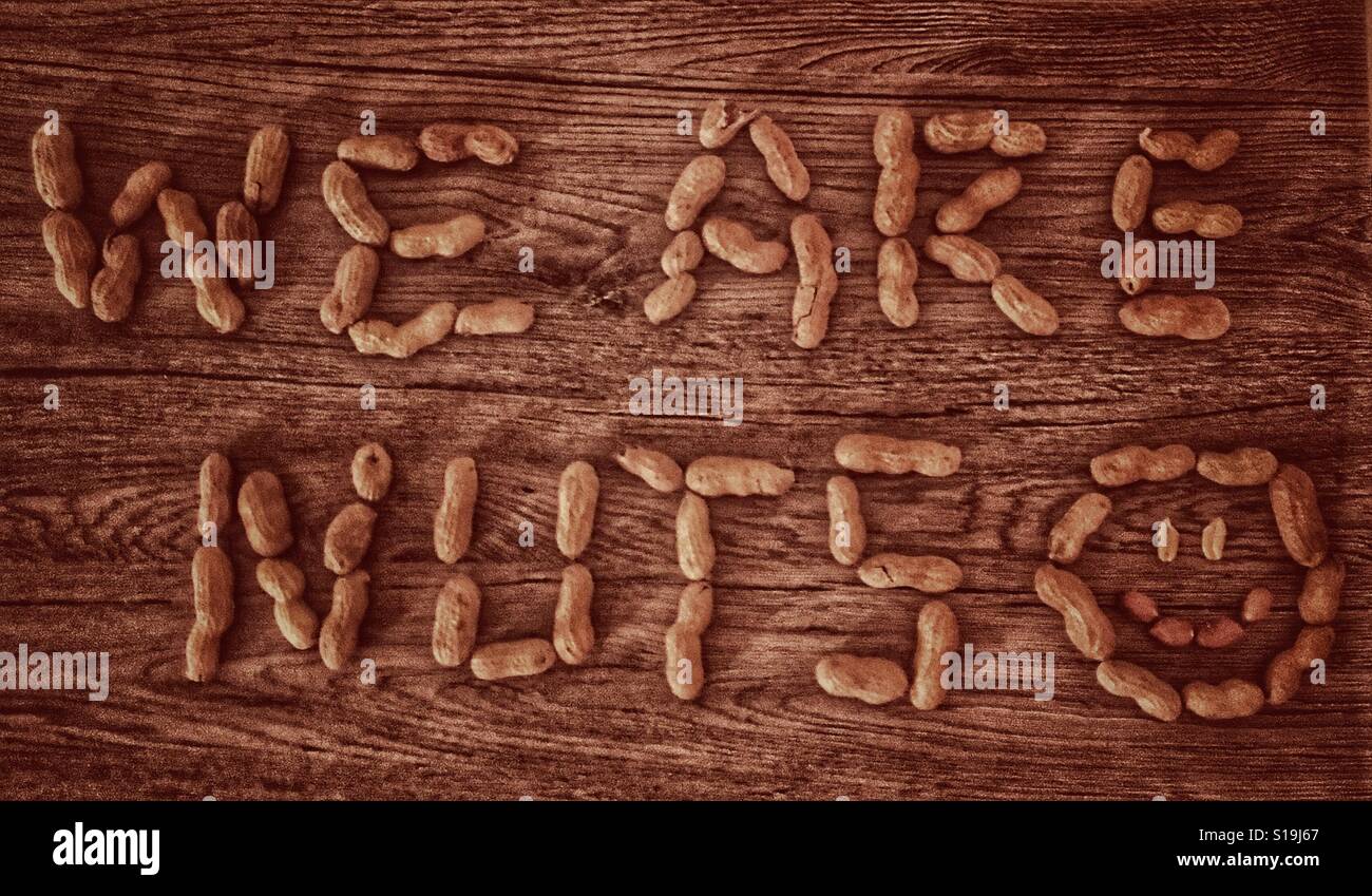 "Wir sind Nuts, geschrieben mit Erdnüssen auf einem hölzernen Tisch und Smiley Gesicht in Ihrer Nähe Stockfoto