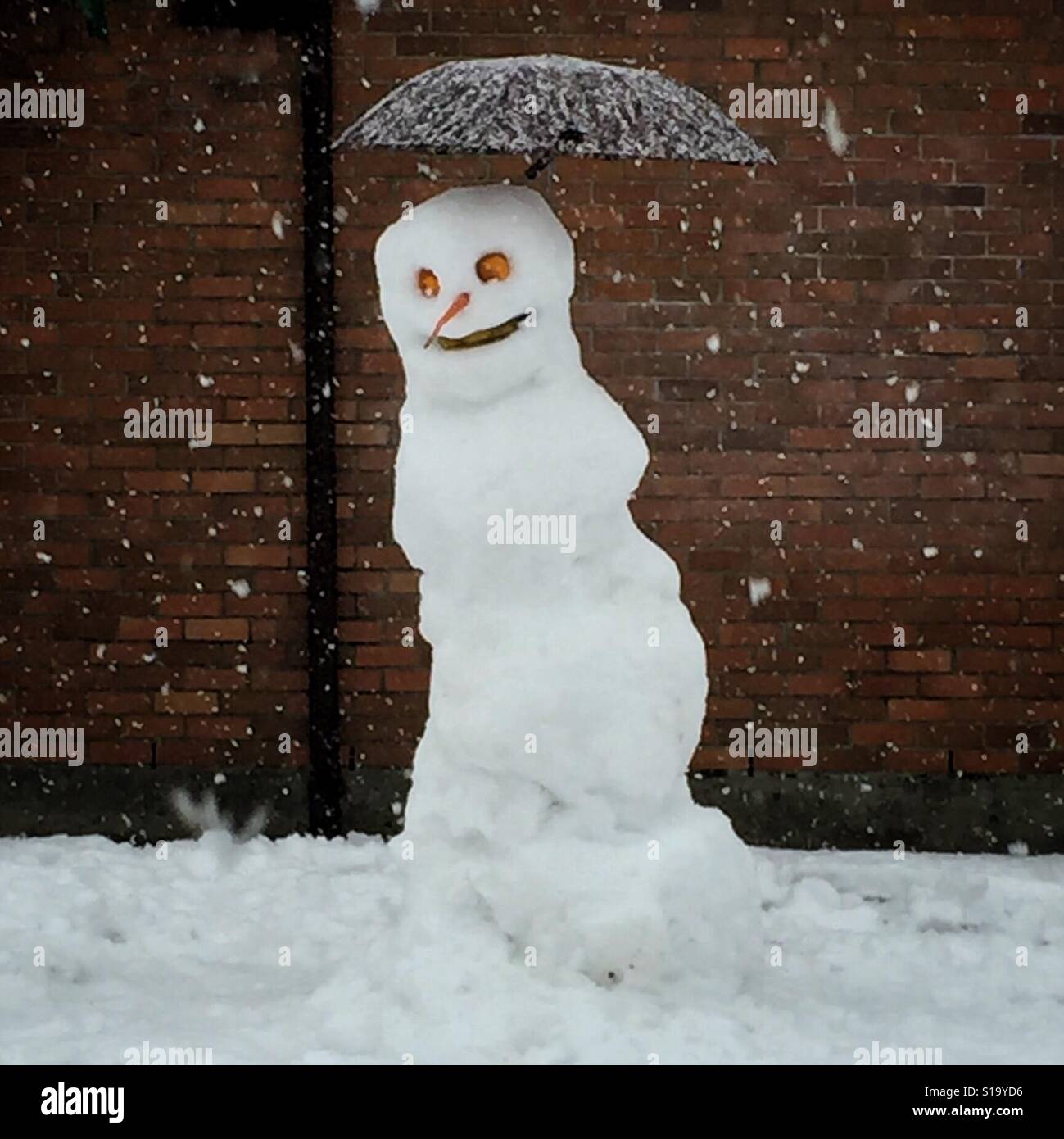 Schneemann mit einem Regenschirm in einem Schneefall Stockfoto