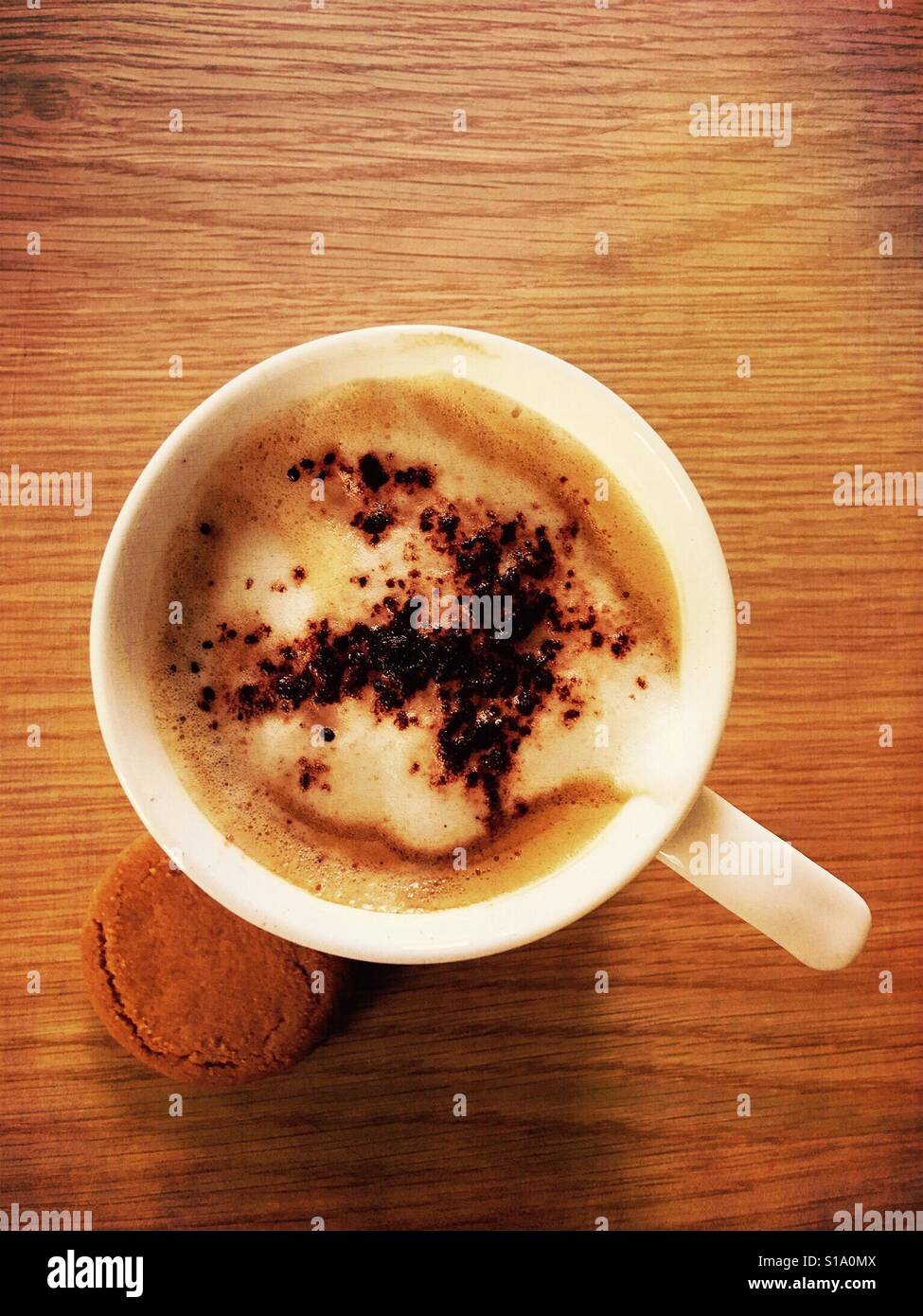 Top-down-Schuss von Schokostreuseln auf Cappuccino mit Ingwer Cookies Stockfoto