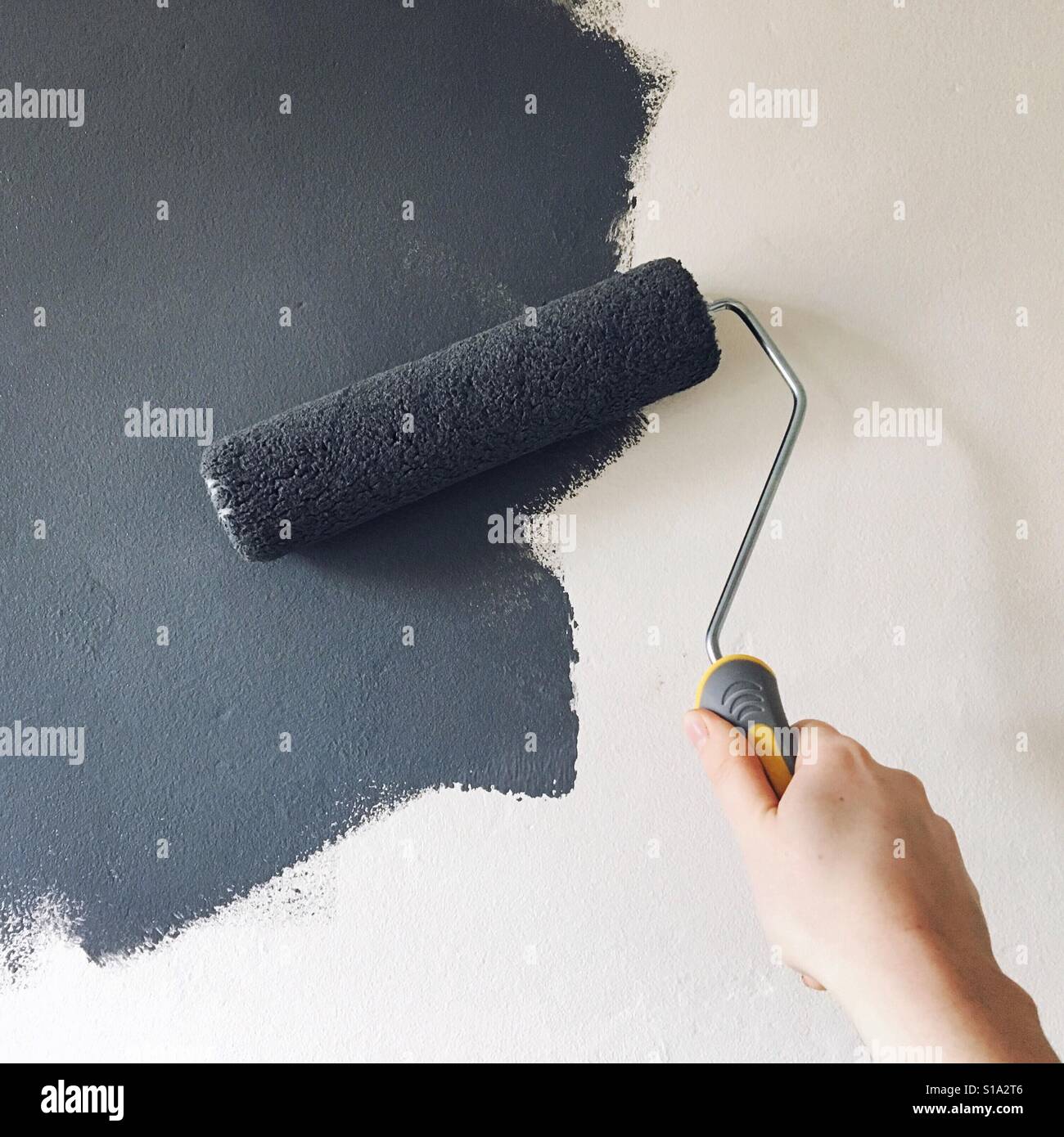 Mit Hilfe einer Walze dunkelgrau Creme Wand malen - Smartphone-aufgenommenes Stockfoto