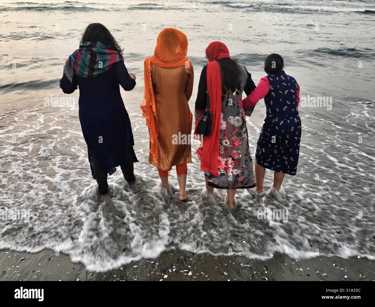 Vier Frauen nass ihre Füße in das Wasser des Meeres. Stockfoto