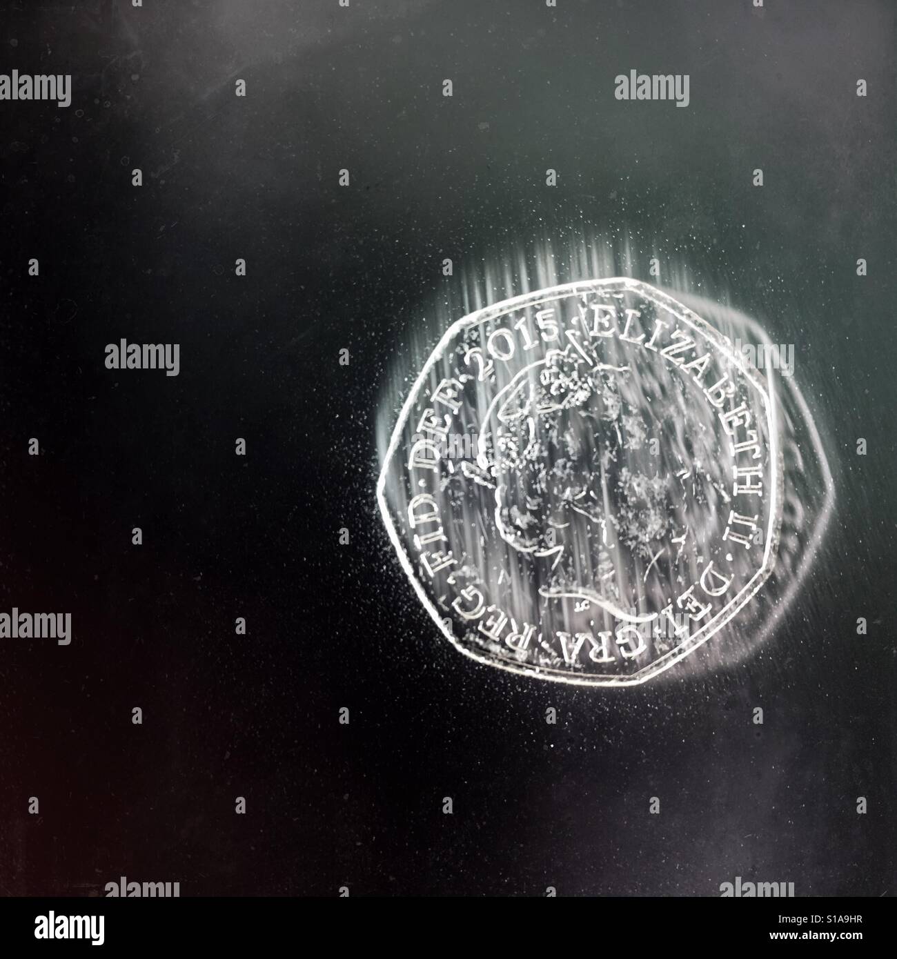 Eine britische 50 Pence-Münze mit Motion blur um die Wirkung des Fallens, vor einem dunklen Hintergrund zu geben. Stockfoto