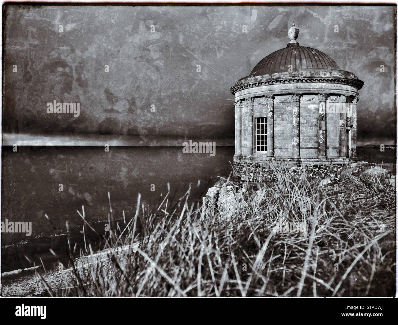 Eine stimmungsvolle & atmosphärischen monochromes Bild von Mussenden Temple, in der Nähe von Castlerock in Co. Londonderry, Nordirland. Dies ist ein kleines rundes Gebäude befindet sich auf einer Klippe über dem Atlantik. Stockfoto