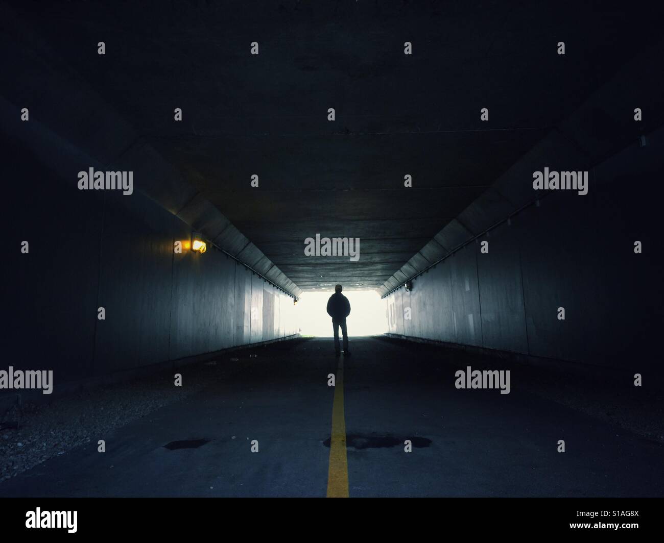 Mann steht am Ende eines dunklen Tunnels Stockfoto