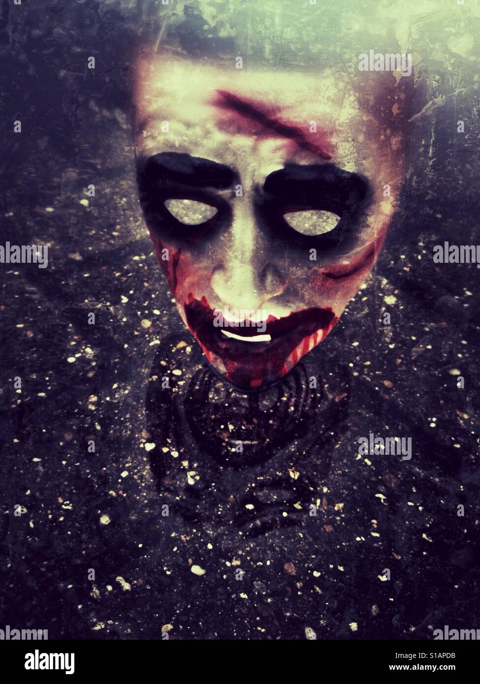 Furchterregende Maske auf nassem Untergrund Stockfoto