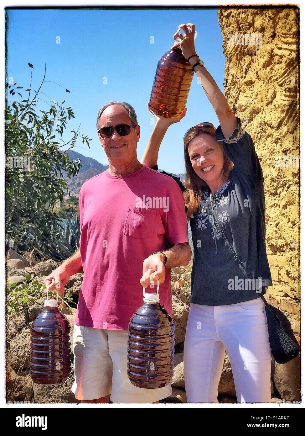 Ein glückliches Paar hält ihre fünf Literflaschen Tequila nach dem Einkaufen in einer Destillerie in Tequila, Mexiko. Stockfoto