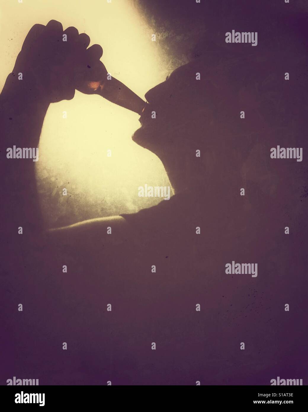 Silhouette eines jungen Mannes aus einer Glasflasche trinken. - Smartphone-aufgenommenes Stockfoto