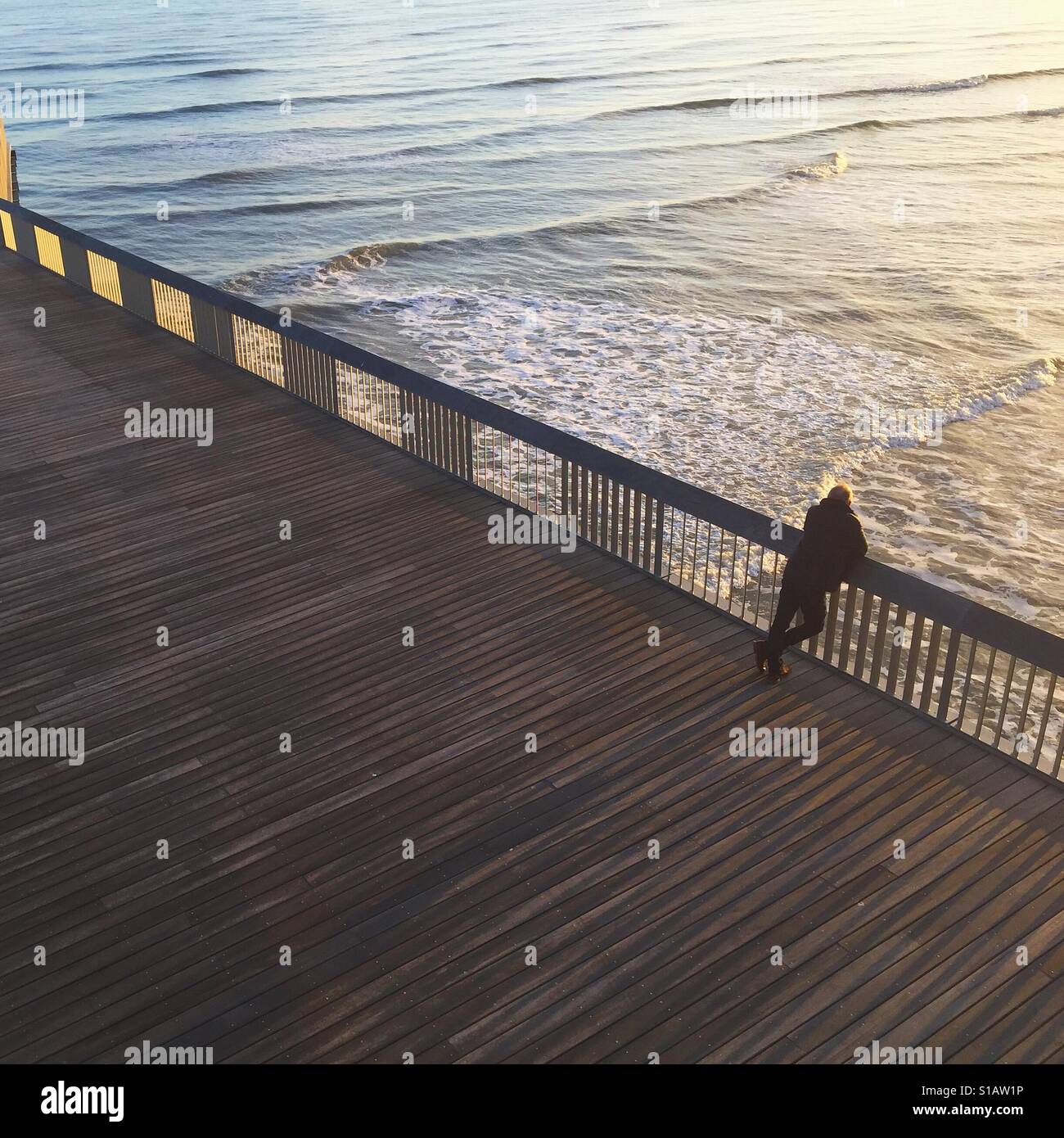 Mann beugte sich über Hastings Pier mit Blick auf das Meer Stockfoto