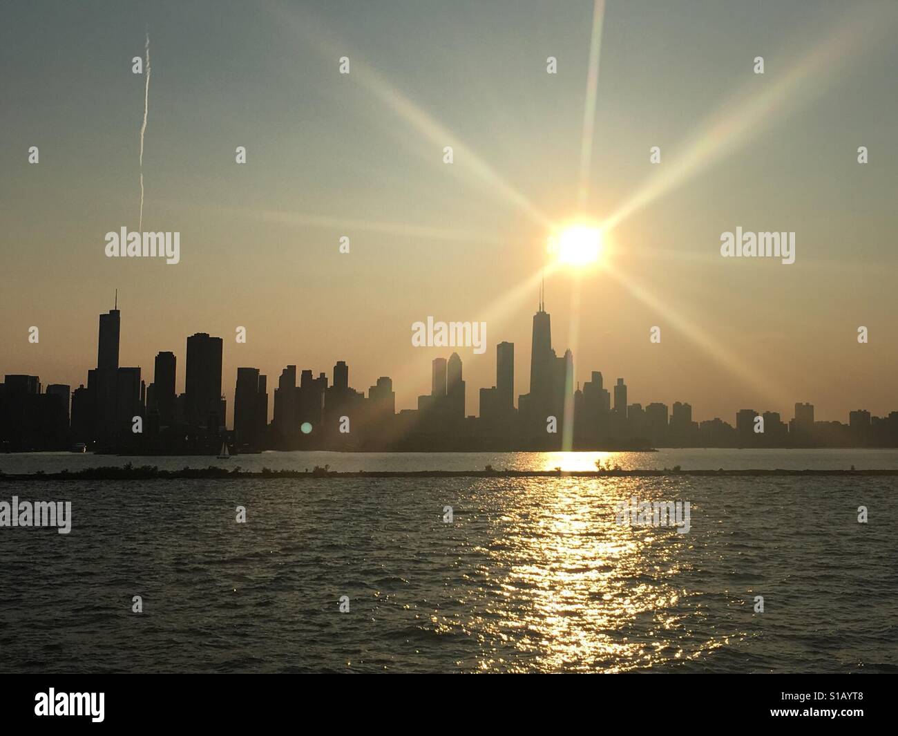 Sonne mit Strahlen Anzeige Einstellung über Chicago vom Lake Michigan im Sommer Stockfoto