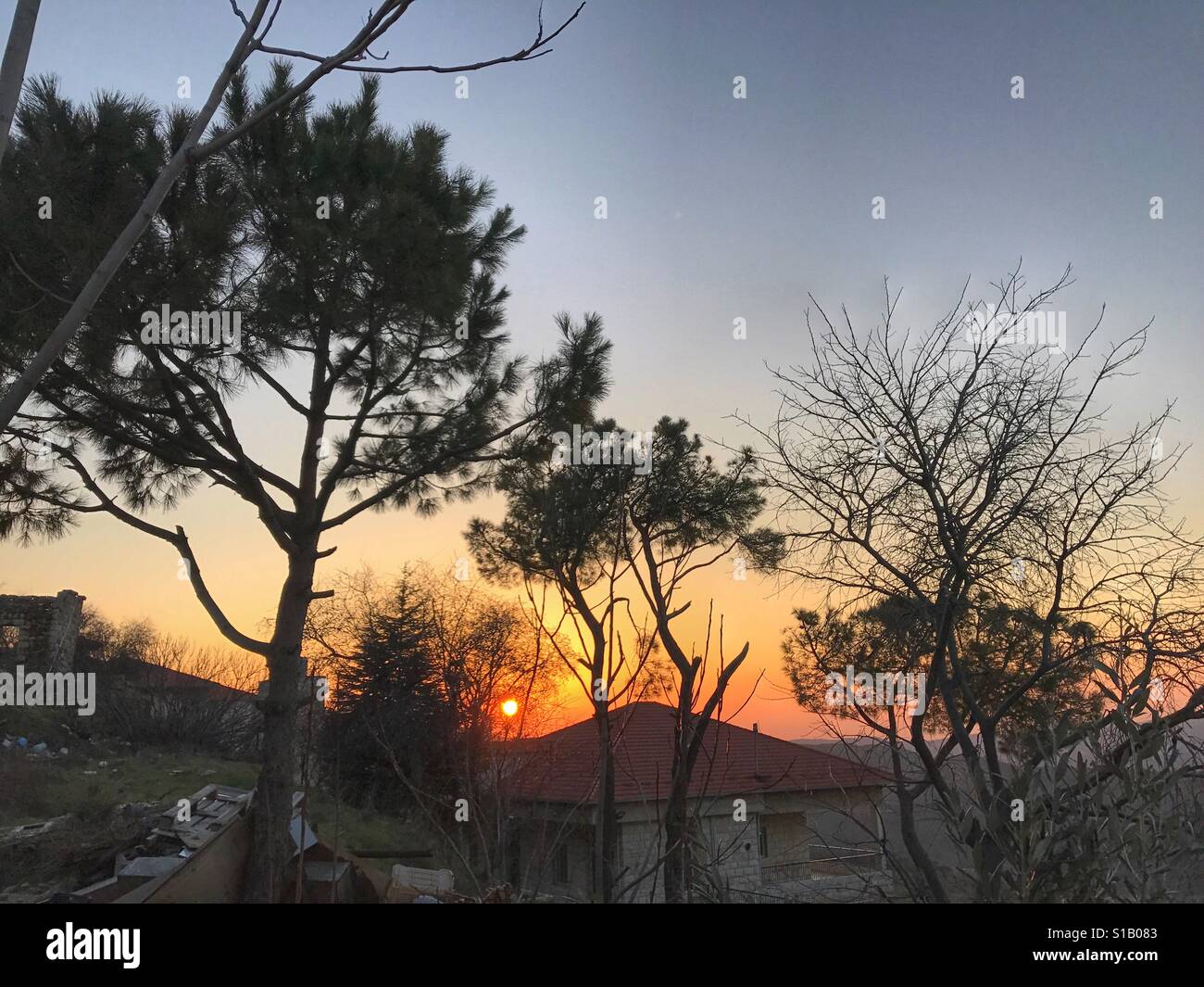 Sonnenuntergang hinter Bäumen und Bergen im Libanon Dorf Ain Zhlata - Nahost - Smartphone-aufgenommenes Stockfoto