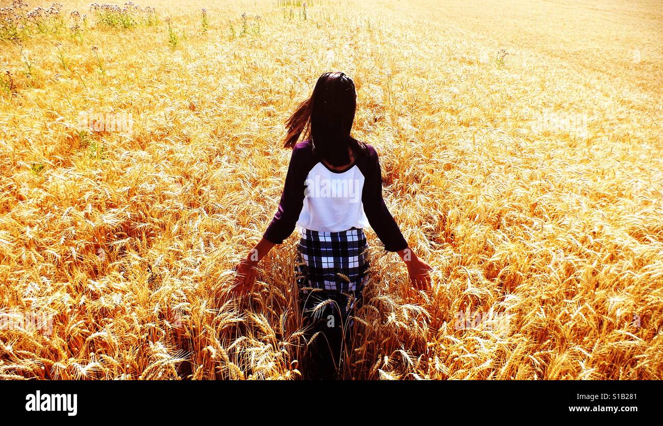 Mädchen zu Fuß in hellen sonnigen Weizenfeld Stockfoto