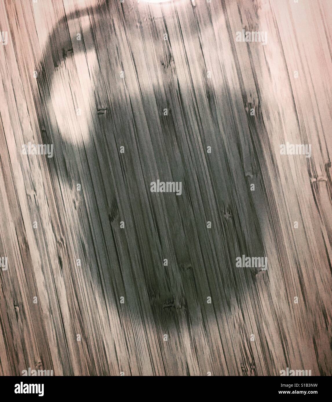 Schatten eines Bechers auf einem Bambus-Oberfläche gegossen Stockfoto