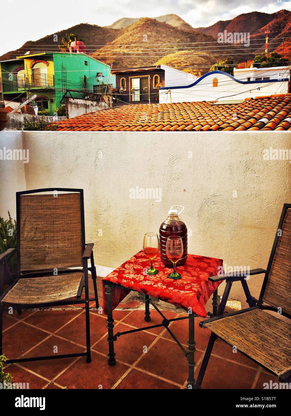 Zwei Gläser und eine Masse aus Kunststoff Krug trinken Tequila sind auf einem kleinen Outdoor-Tisch auf einem Hof in Jalisco, Mexiko. Stockfoto