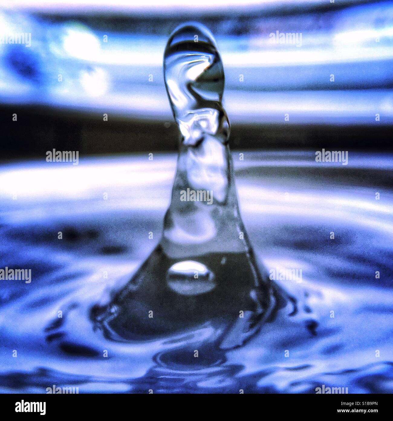 Close-up iPhone Foto mit einem Makro-Objektiv-Anhang eines Wassertropfens Spritzwasser in einer Lache des Wassers. Stockfoto