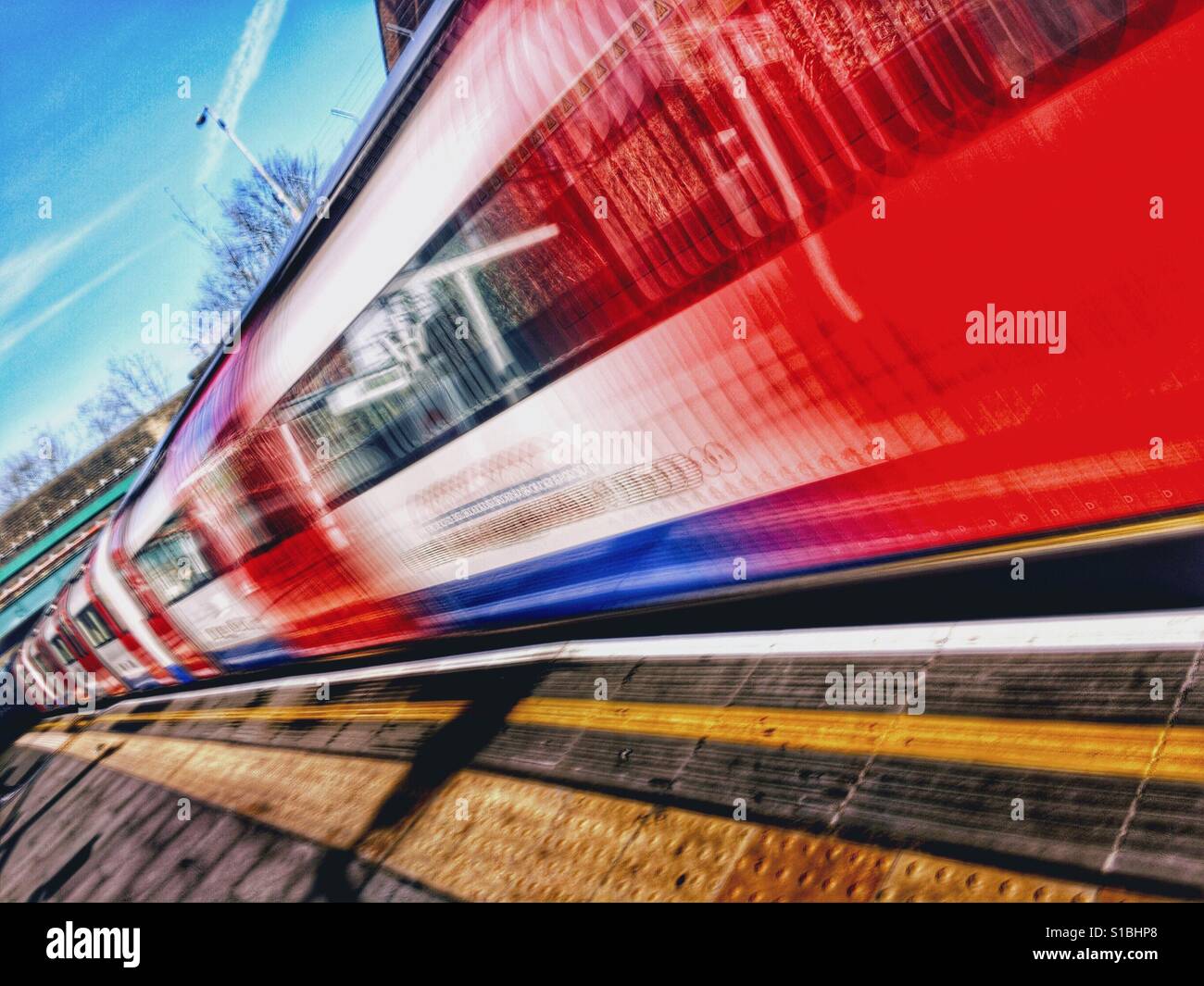 iPhone slow-Shutter app Bewegungsunschärfe Foto von einem Londoner U-Bahn Zug ziehen in eine leere Plattform an einem sonnigen Tag in London, England, UK. Stockfoto