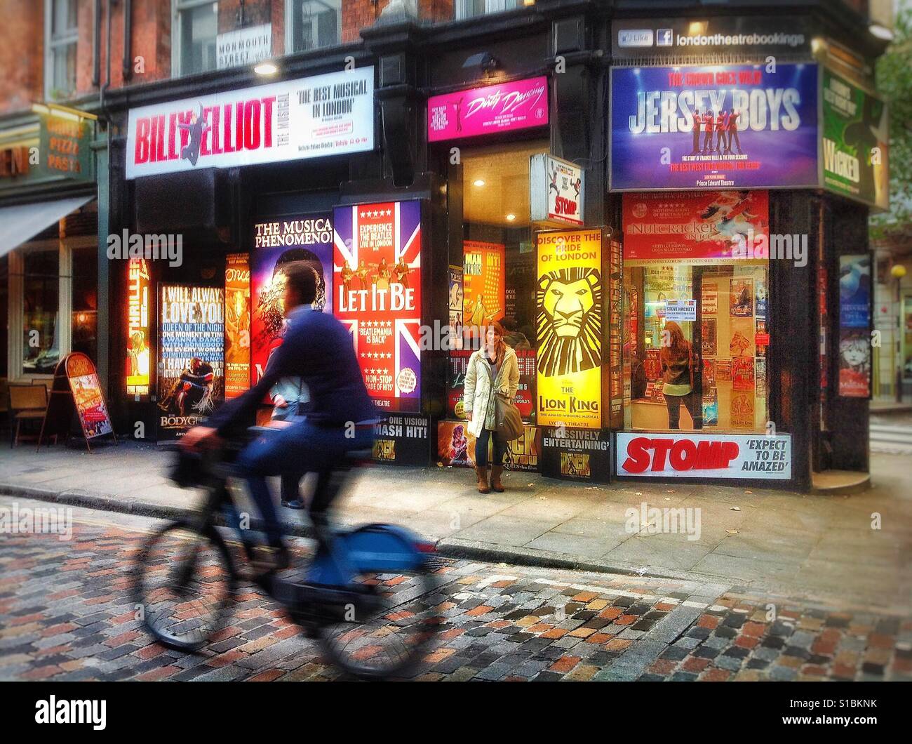 Showtime! Ticket-Agentur für Shows, Musicals, Theater, Konzerte und Veranstaltungen an der Ecke der Monmouth Street und Shaftesbury Avenue, London mit beleuchteten Großflächenplakate und bunten displays Stockfoto