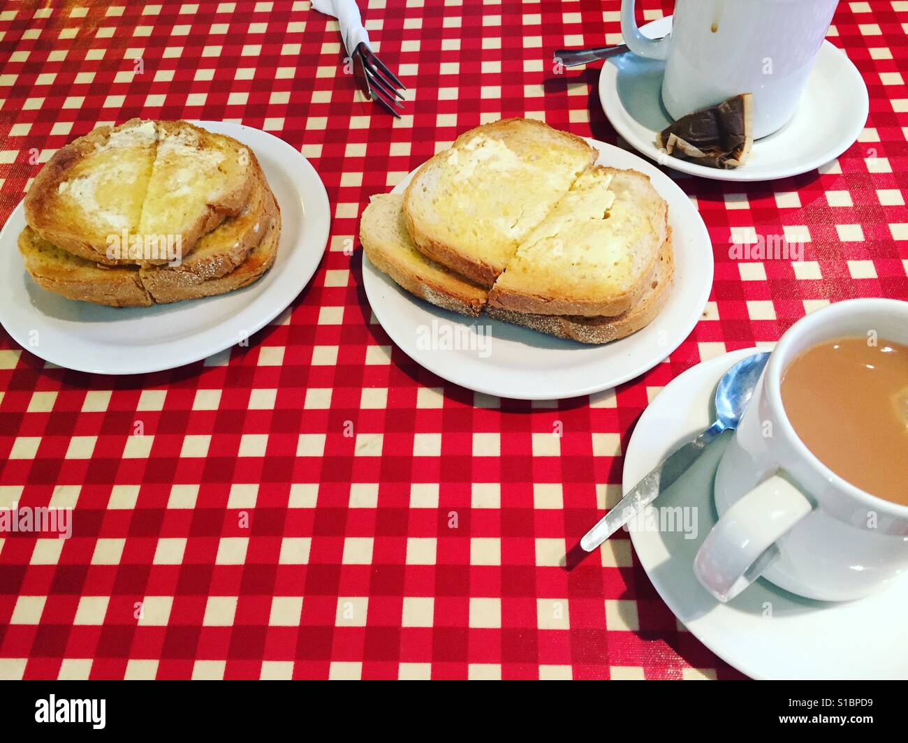 Tee und Toast auf roten Tischdecke Stockfoto
