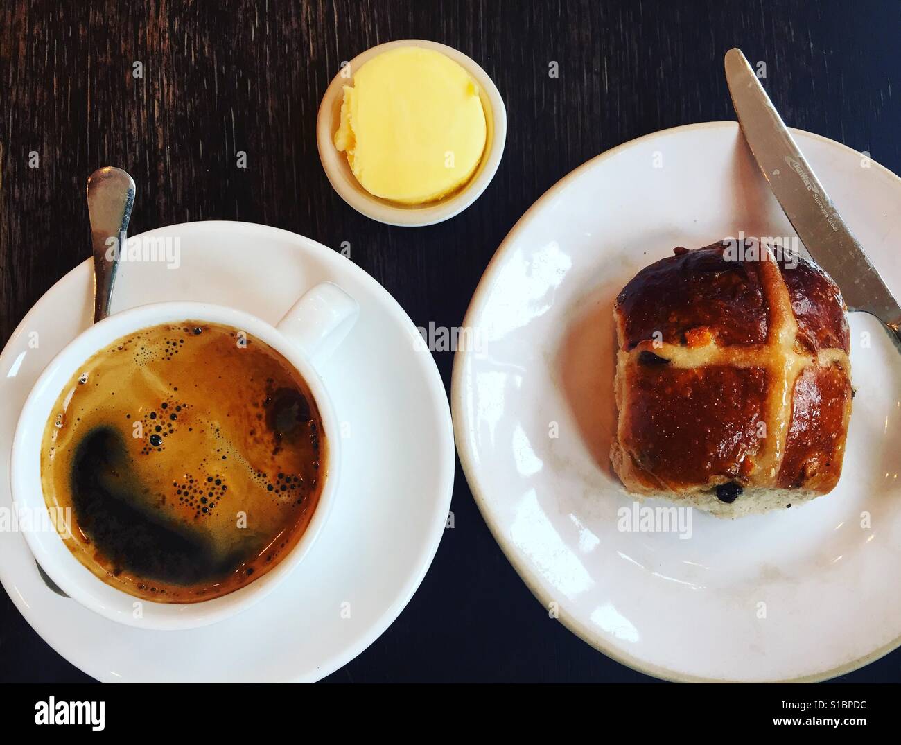 Schwarzer Kaffee und Hot Cross bun Stockfoto