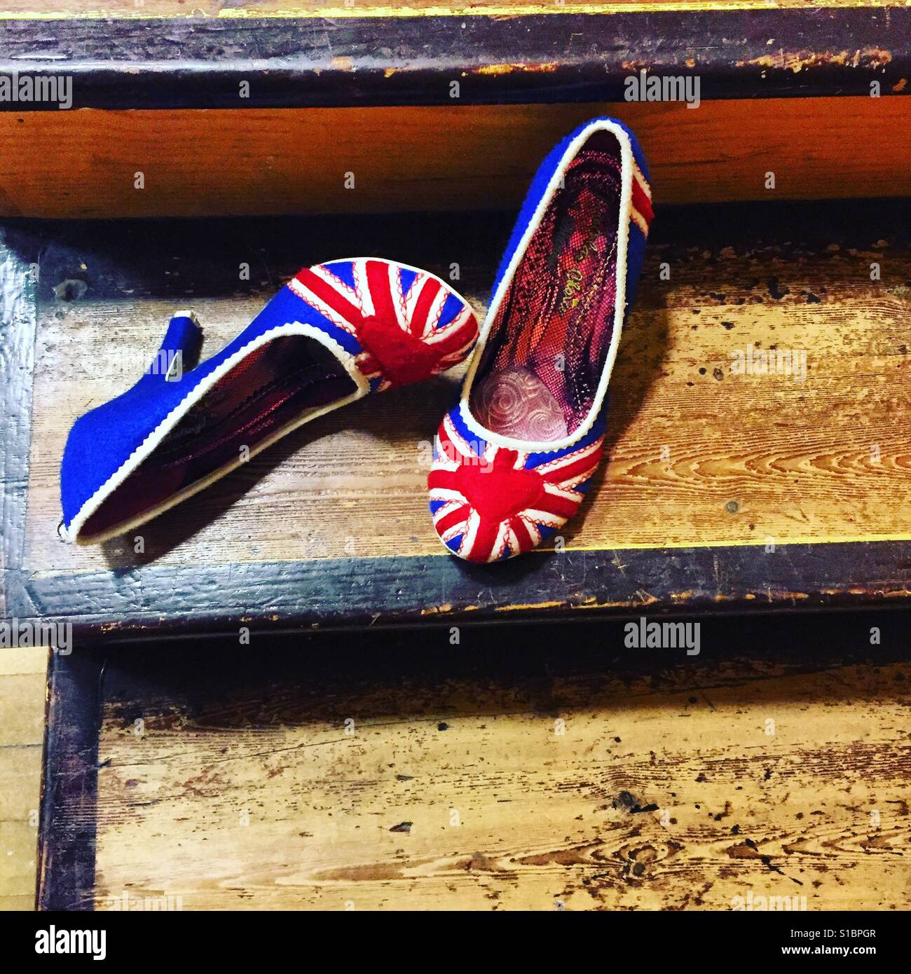 Union Jack-hohe Hölle-Schuhe auf Holzstufen Stockfoto