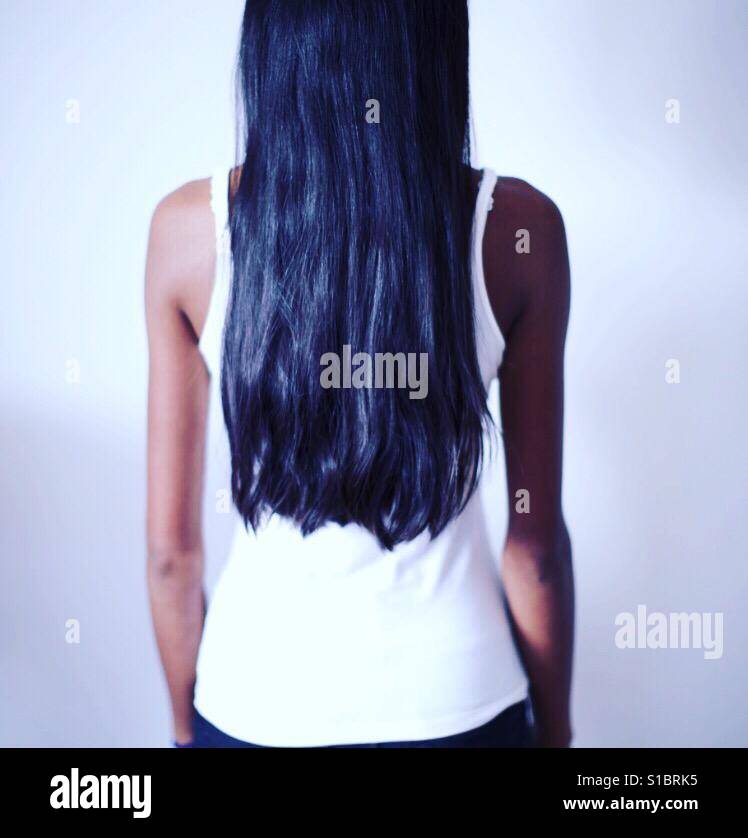 Lange schwarze Haare eines Mädchens erschossen von der Rückseite mit einer weißen Weste Stockfoto